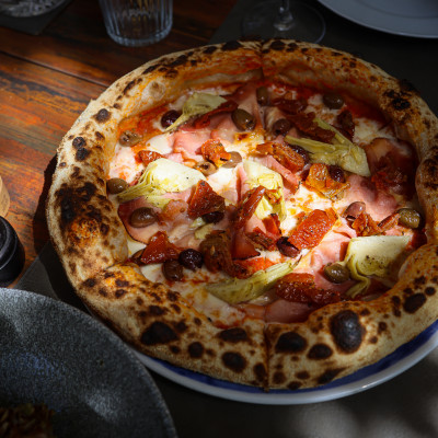 Pizza Capricciosa Sbagliata cu sos din roșii, mozzarella „fior di latte", speck, anghinare, masline Leccino si rosii uscate
